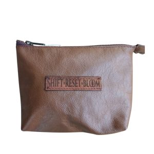 small leather essentials bag with zip closure unlined laser engraved words on outer panel shift reset bloom